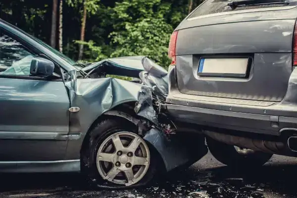 Two cars are shown after a rear-end collision, with the front vehicle's bumper and hood severely damaged